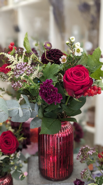 Ruby Romance Vase - A striking vase arrangement featuring rich ruby red, deep burgundy and soft seasonal blooms, beautifully handcrafted with fresh foliage.